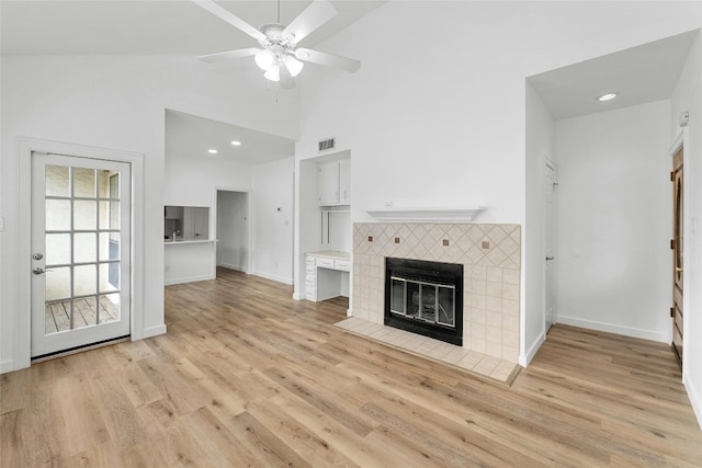 unfurnished living room with high vaulted ceiling, a fireplace, light hardwood / wood-style floors, and ceiling fan