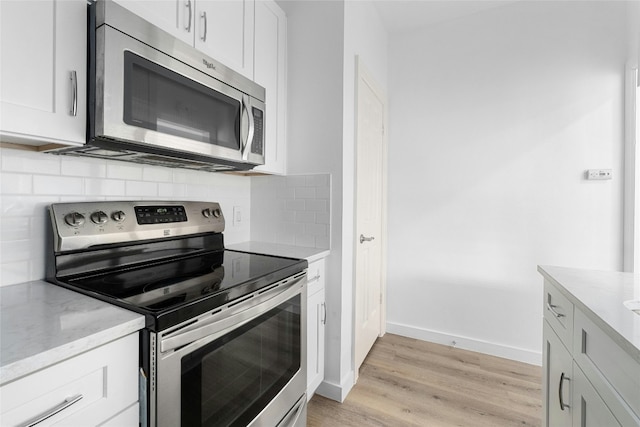 kitchen with white cabinetry, appliances with stainless steel finishes, light wood-type flooring, and decorative backsplash