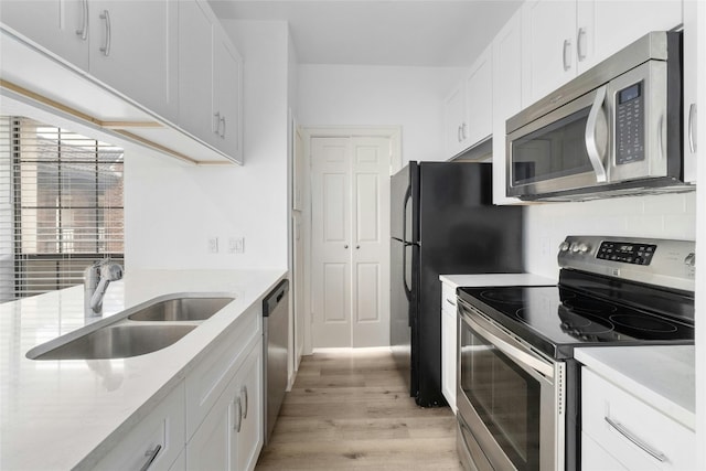 kitchen featuring sink, white cabinetry, stainless steel appliances, light hardwood / wood-style floors, and decorative backsplash