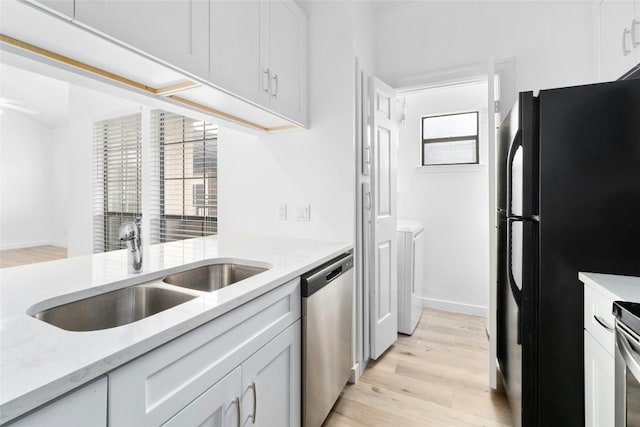 kitchen with sink, white cabinetry, light hardwood / wood-style flooring, stainless steel appliances, and light stone countertops