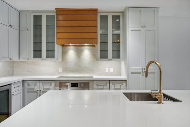 kitchen with tasteful backsplash, sink, oven, beverage cooler, and black electric stovetop