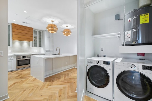 laundry area featuring separate washer and dryer, sink, water heater, and light parquet flooring