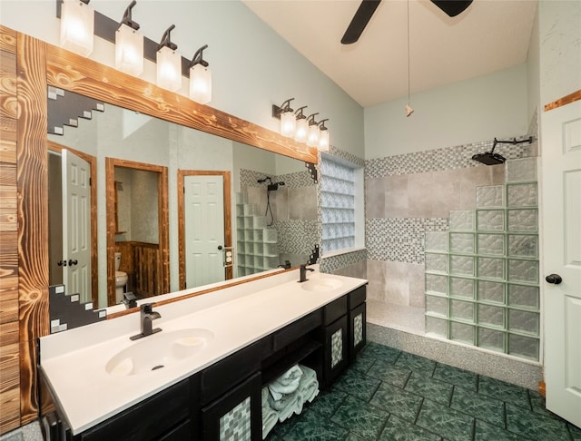 bathroom with ceiling fan, vanity, toilet, and a tile shower