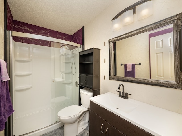 bathroom featuring vanity, toilet, a shower with shower door, and a textured ceiling