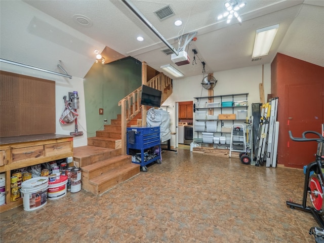 garage featuring a garage door opener, washer / dryer, and a workshop area