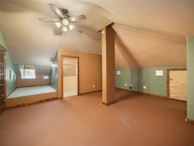 bonus room with ceiling fan, vaulted ceiling, and a textured ceiling