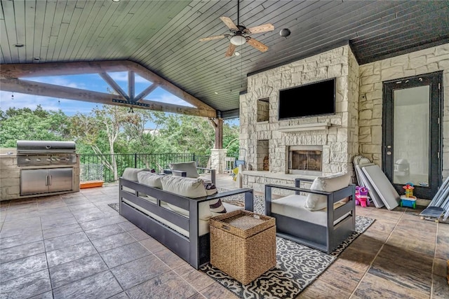 view of patio featuring ceiling fan, area for grilling, and an outdoor living space with a fireplace