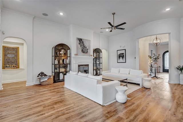 living room with ceiling fan, ornamental molding, and light hardwood / wood-style floors