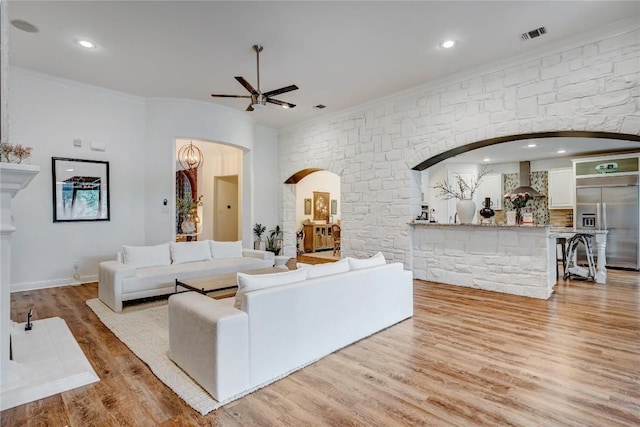 living room featuring crown molding, ceiling fan, and light wood-type flooring