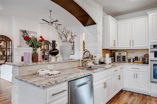 kitchen with sink, stainless steel dishwasher, kitchen peninsula, and white cabinets