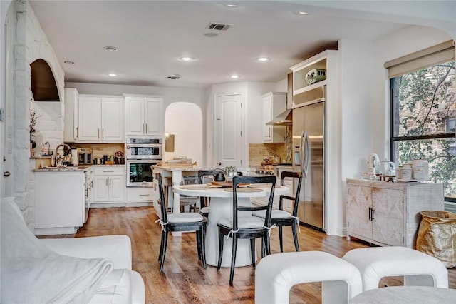 kitchen with stainless steel appliances, white cabinetry, a kitchen island, and light wood-type flooring