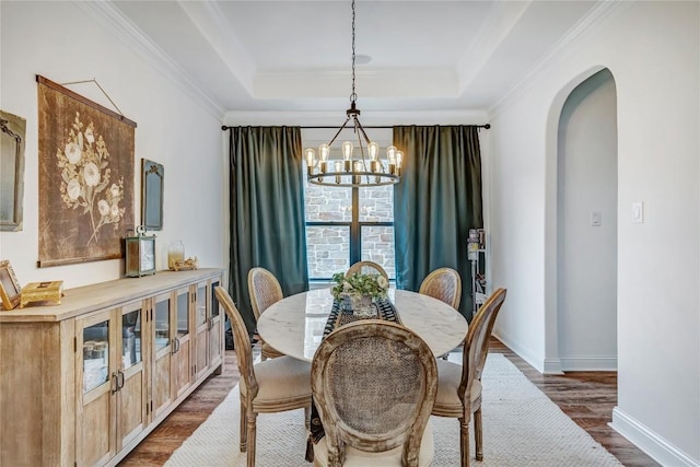 dining room with dark hardwood / wood-style flooring, crown molding, a raised ceiling, and a chandelier