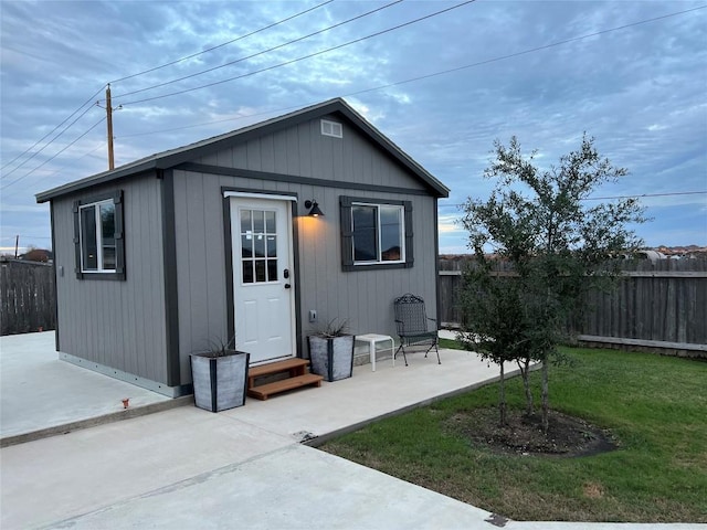 rear view of house featuring a yard, an outdoor structure, and a patio