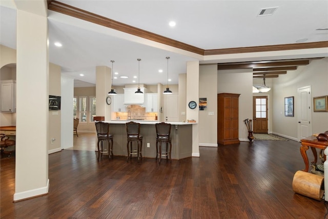 kitchen with a kitchen breakfast bar, dark hardwood / wood-style floors, ornamental molding, white cabinets, and decorative light fixtures