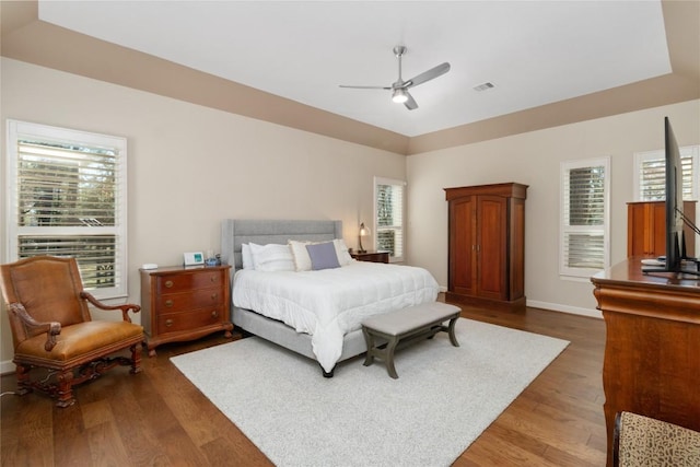 bedroom with dark hardwood / wood-style flooring, a tray ceiling, vaulted ceiling, and ceiling fan