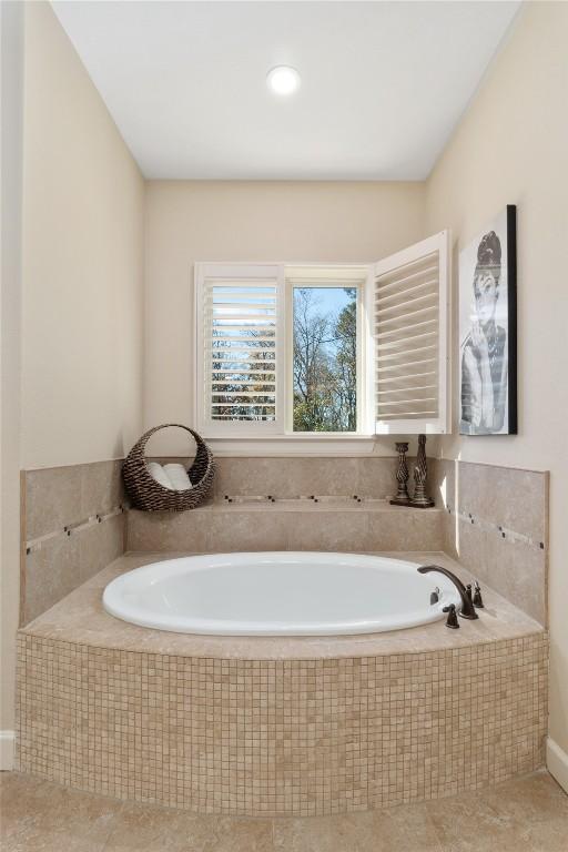 bathroom with tile patterned floors and tiled tub