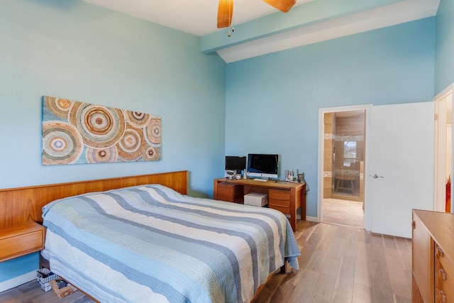 bedroom featuring ensuite bath, light hardwood / wood-style flooring, and vaulted ceiling with beams