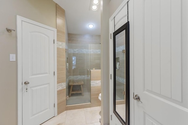 bathroom featuring a shower with door, tile patterned floors, and toilet