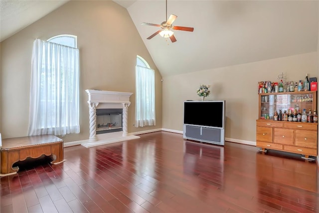 living room with ceiling fan, high vaulted ceiling, a healthy amount of sunlight, and dark hardwood / wood-style floors