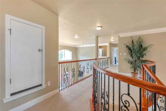 corridor featuring crown molding, a textured ceiling, and carpet flooring