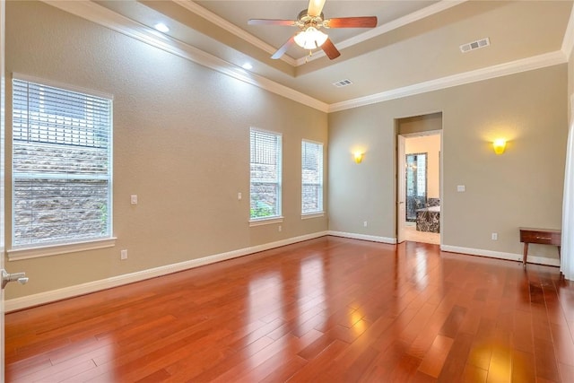 unfurnished room featuring hardwood / wood-style floors, plenty of natural light, ornamental molding, and a raised ceiling