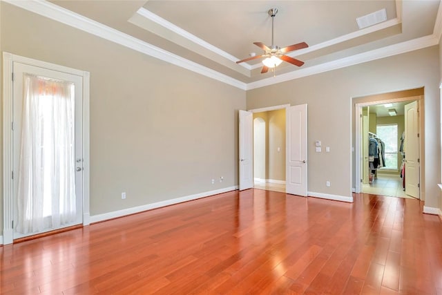 spare room featuring a tray ceiling, wood-type flooring, ornamental molding, and ceiling fan