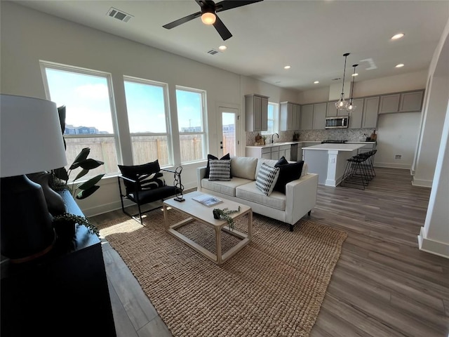 living room featuring dark wood-type flooring, ceiling fan, and sink