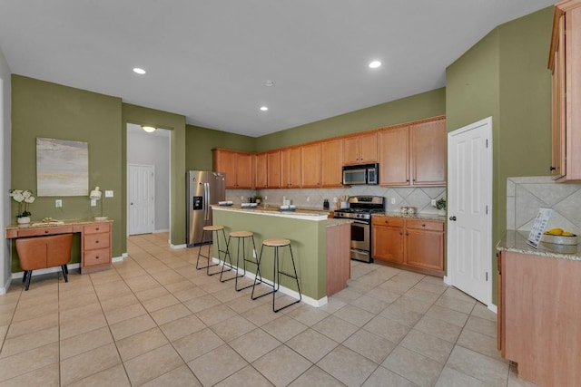 kitchen featuring a kitchen island, appliances with stainless steel finishes, backsplash, a kitchen breakfast bar, and light tile patterned floors