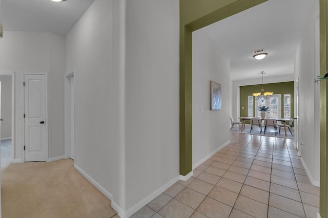 hallway featuring an inviting chandelier and light tile patterned floors