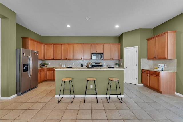 kitchen with appliances with stainless steel finishes, a center island, a breakfast bar area, and light tile patterned floors