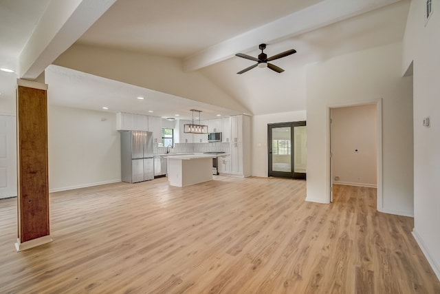 unfurnished living room featuring ceiling fan, sink, light hardwood / wood-style floors, and vaulted ceiling with beams