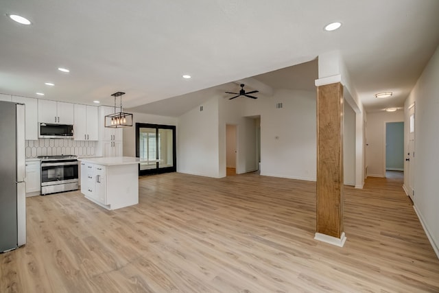 kitchen featuring lofted ceiling, a center island, appliances with stainless steel finishes, pendant lighting, and white cabinets