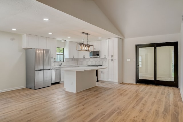 kitchen featuring decorative light fixtures, light hardwood / wood-style flooring, a kitchen island, stainless steel appliances, and white cabinets