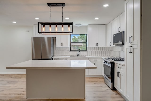 kitchen with white cabinetry, sink, hanging light fixtures, a center island, and stainless steel appliances