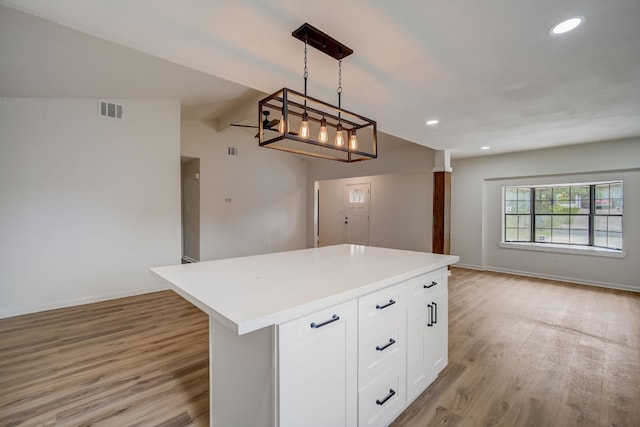 kitchen featuring a kitchen island, white cabinets, light hardwood / wood-style floors, and decorative light fixtures