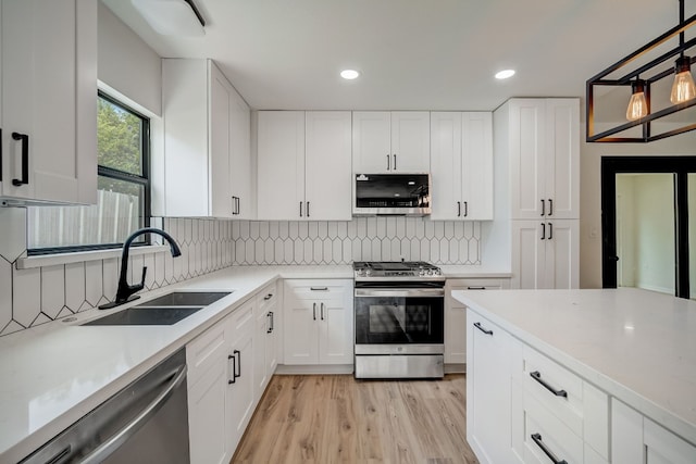 kitchen featuring tasteful backsplash, white cabinetry, appliances with stainless steel finishes, and sink