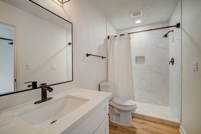 bathroom with walk in shower, toilet, wood-type flooring, a textured ceiling, and vanity