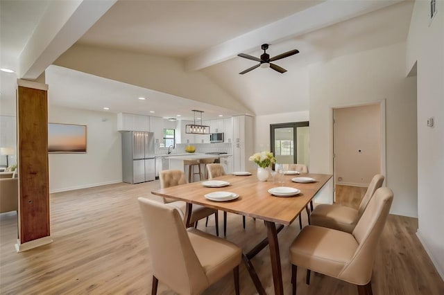 dining room featuring ceiling fan, sink, light hardwood / wood-style floors, and vaulted ceiling with beams