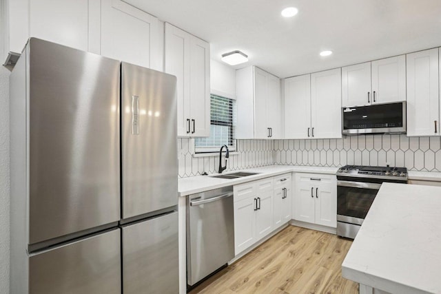 6009 Glen Meadow Dr, Austin, TX 78745 - kitchen with stainless steel appliances, light wood-style floors, decorative backsplash, white cabinetry, and recessed lighting