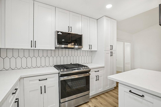 6009 Glen Meadow Dr, Austin, TX 78745 - kitchen with appliances with stainless steel finishes, white cabinets, decorative backsplash, light wood-style floors, and recessed lighting