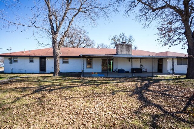 back of property with a lawn and a patio area