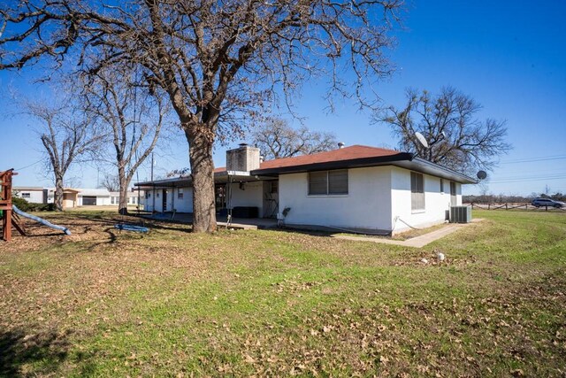 back of house with a playground, a yard, and central AC unit