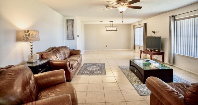 tiled living room featuring ceiling fan with notable chandelier