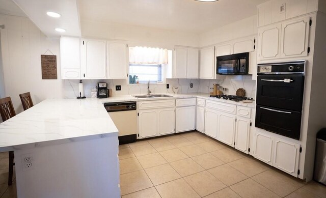 kitchen with sink, a breakfast bar, white cabinetry, black appliances, and kitchen peninsula