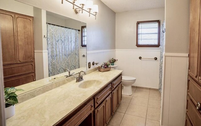 bathroom featuring tile patterned flooring, vanity, toilet, and a textured ceiling