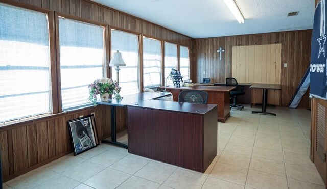 home office featuring light tile patterned floors, a textured ceiling, and wood walls