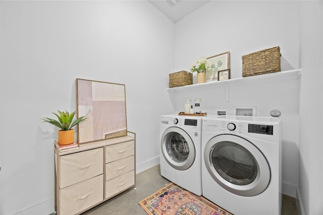 washroom featuring baseboards, separate washer and dryer, and laundry area