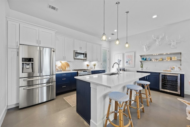 kitchen with finished concrete flooring, visible vents, a sink, appliances with stainless steel finishes, and blue cabinets