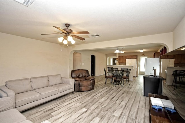 living room with ceiling fan, sink, a textured ceiling, and light wood-type flooring