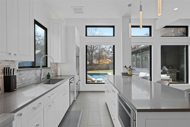 kitchen with pendant lighting, sink, white cabinetry, and a center island